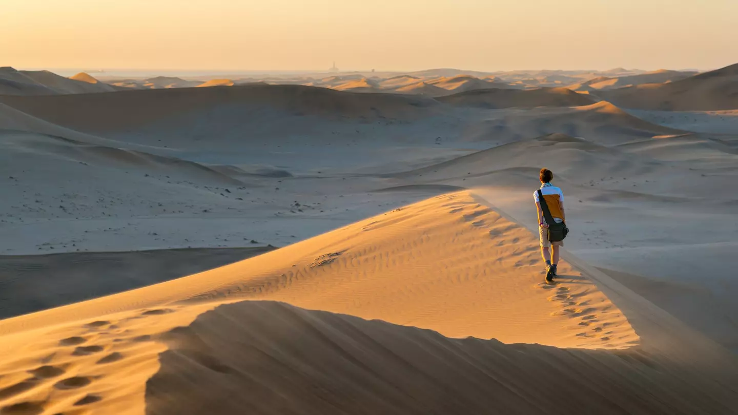 A tourist walks on the scenic dunes of Sossusvlei, Namib desert, Namib-Naukluft National Park, Namibia, Africa