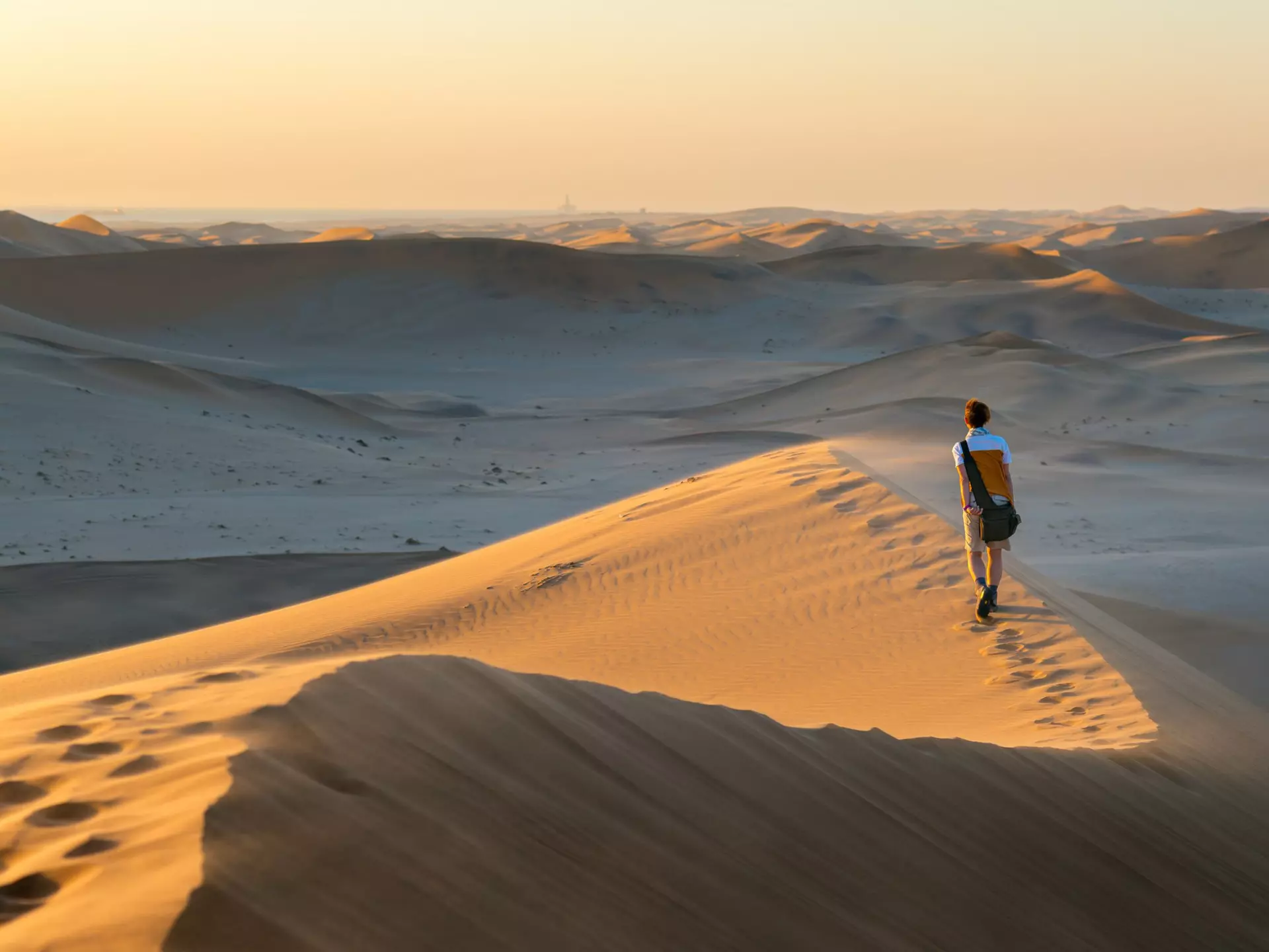 A tourist walks on the scenic dunes of Sossusvlei, Namib desert, Namib-Naukluft National Park, Namibia, Africa