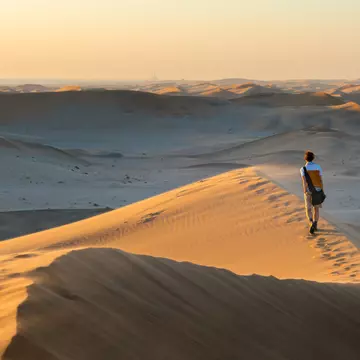 A tourist walks on the scenic dunes of Sossusvlei, Namib desert, Namib-Naukluft National Park, Namibia, Africa