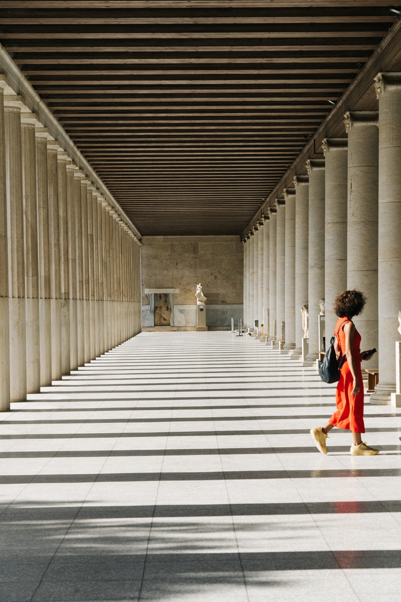 A woman in an orange dress explores the Roman Agora in Athens, Greece.
