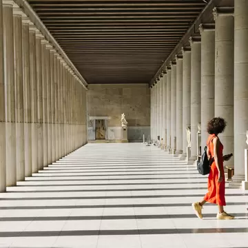 A woman in an orange dress explores the Roman Agora in Athens, Greece.