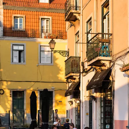 Diners sit on a cafe terrace while the evening sun illuminates the surrounding buildings.