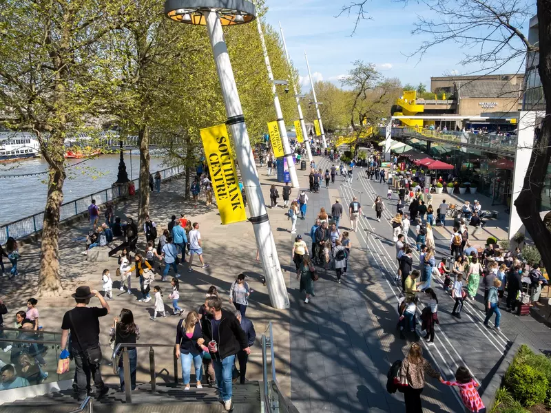 Elevated view of London's South Bank promenade bustling with people enjoying the local atmosphere.