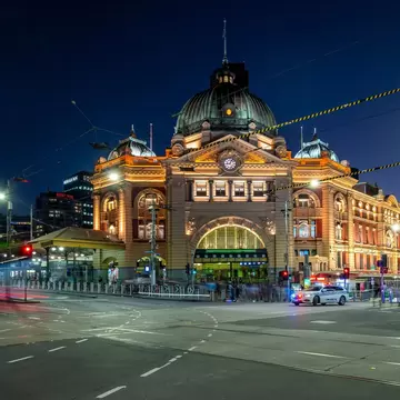 Flinders St station by night, with passing trams and traffic creating light trails motion blur
