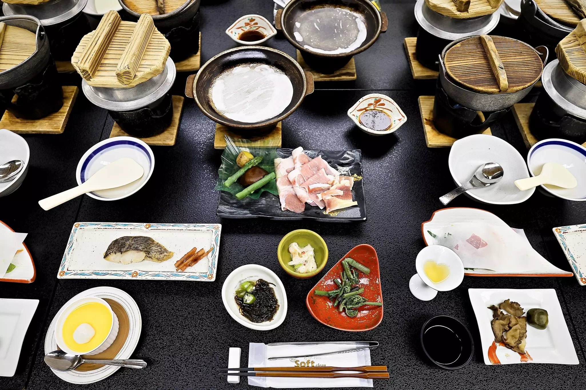 A table at a fine-dining restaurant is set with multiple dishes and bowls.