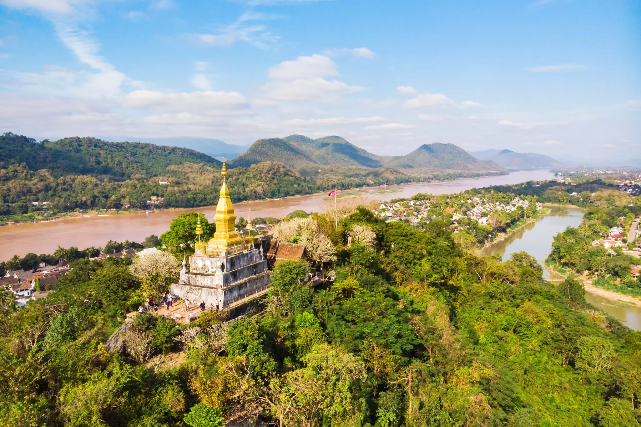 View of town and surrounding countryside. golden pagoda of Wat Chom Si on the top of Mount Phou Si.