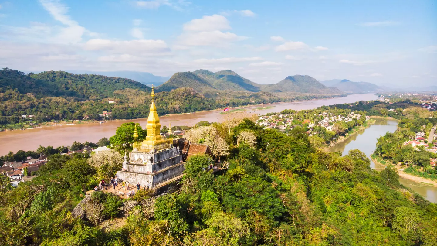 View of town and surrounding countryside. golden pagoda of Wat Chom Si on the top of Mount Phou Si.