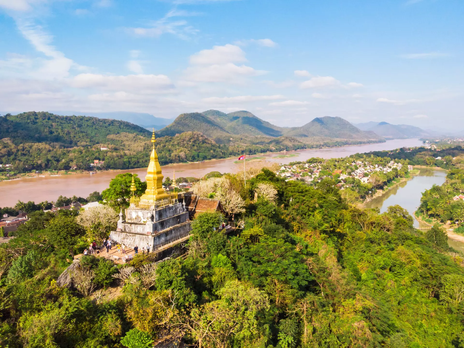 View of town and surrounding countryside. golden pagoda of Wat Chom Si on the top of Mount Phou Si.