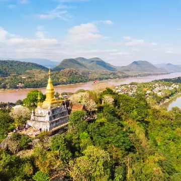 View of town and surrounding countryside. golden pagoda of Wat Chom Si on the top of Mount Phou Si.
