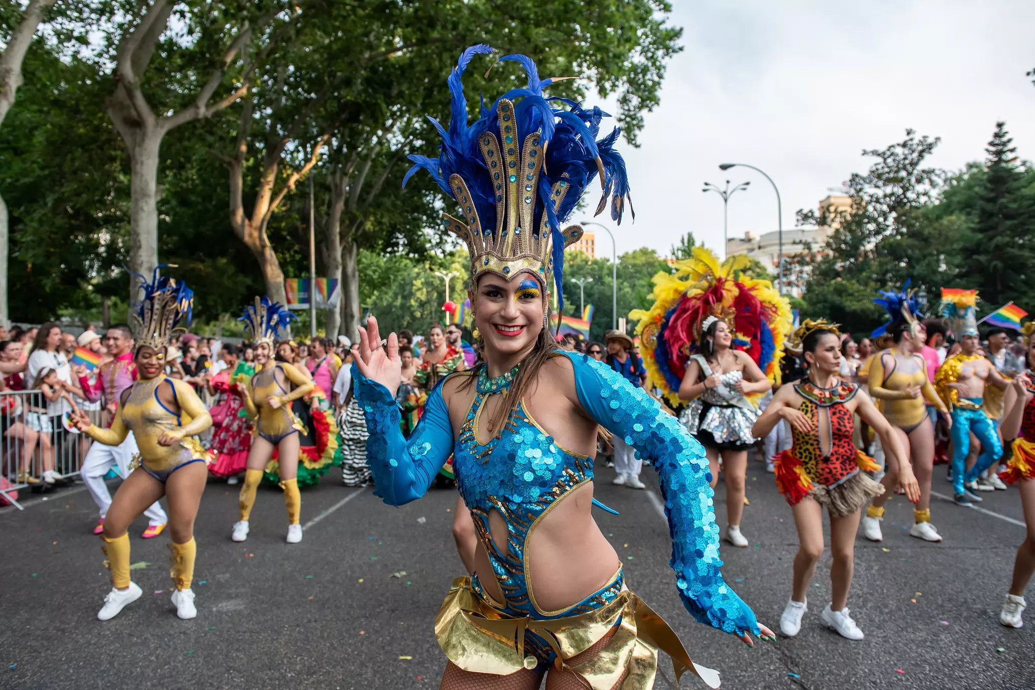 A person in a festive costume dances in the street during a parade.