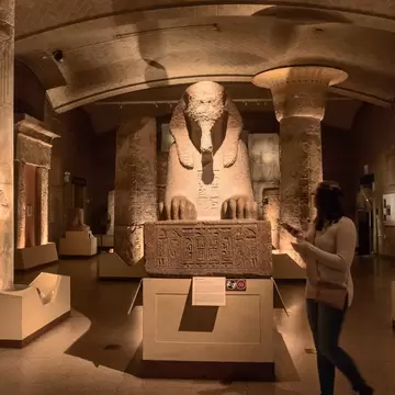 A person walks past the Sphinx of Ramses II in a darkened room in the Penn Museum in Philadelphia