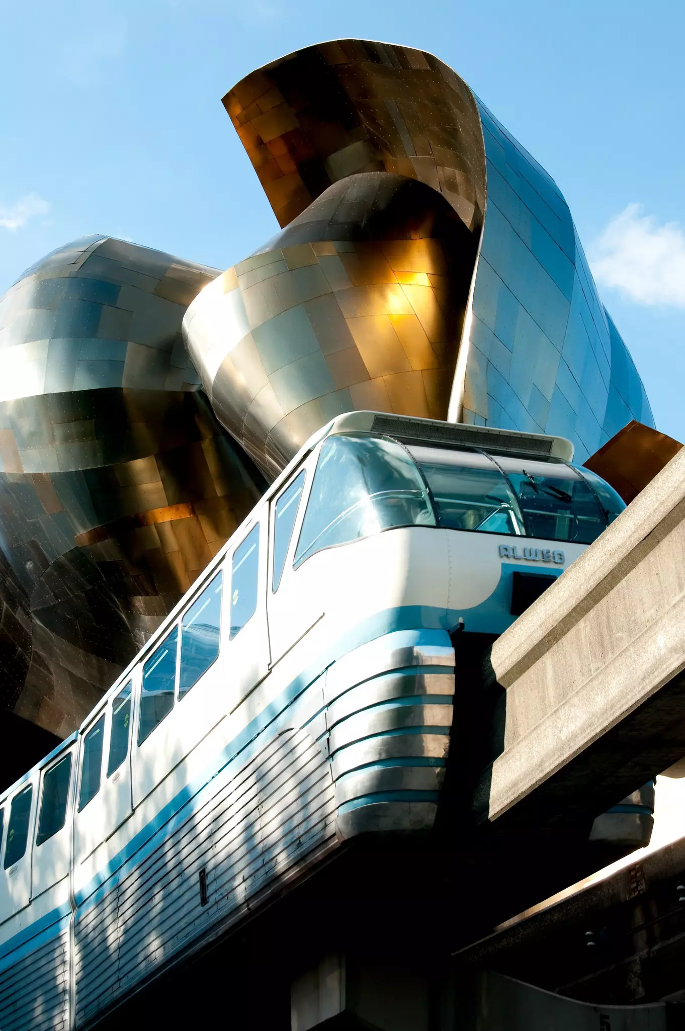 The Seattle Monorail entering the Seattle Center through the Experience Music Project on a sunny day. The Monorail was originally built in 1962 for the Worlds Fair.