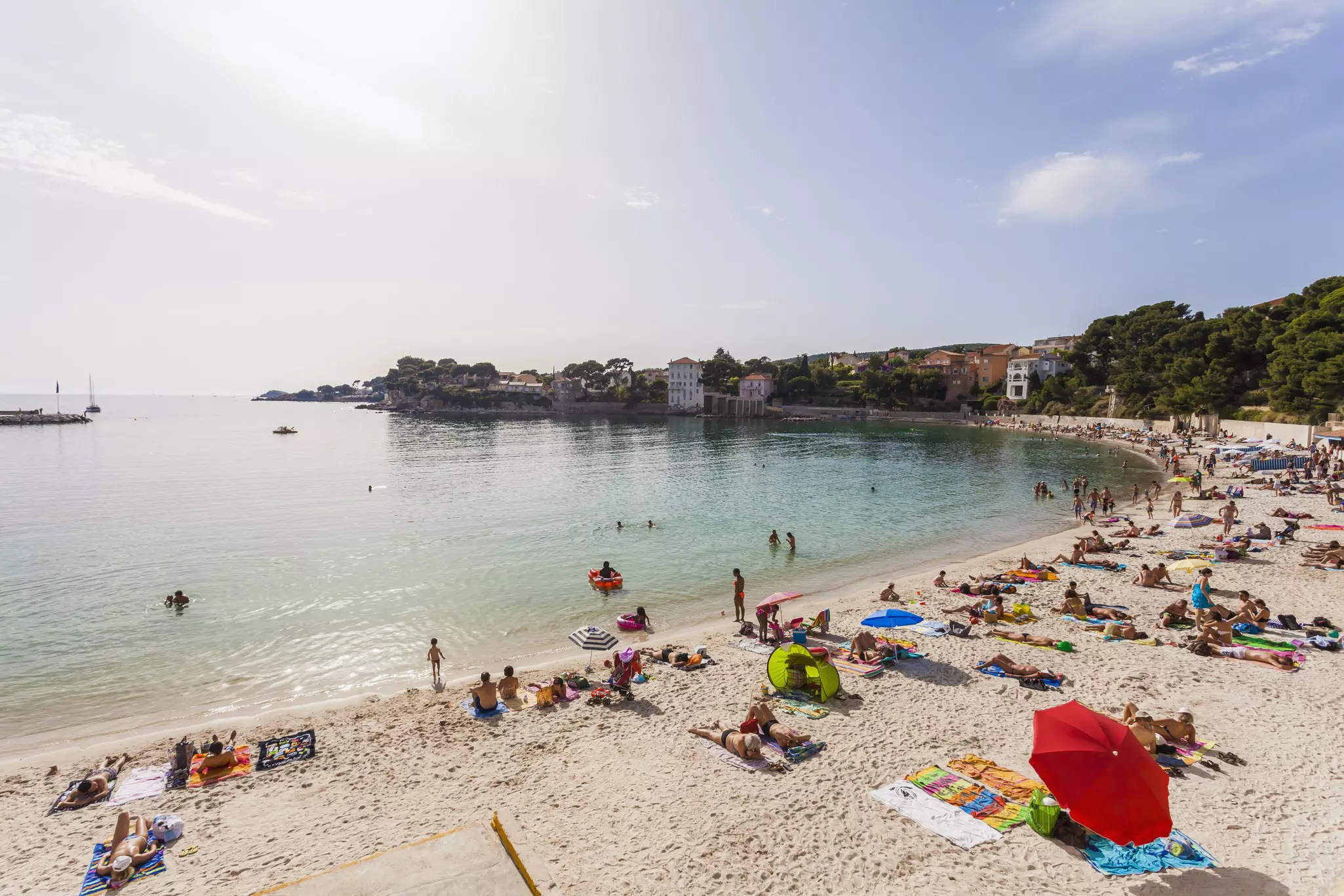 People laying on colorful towels and under bright parasols on a sandy beach in summer