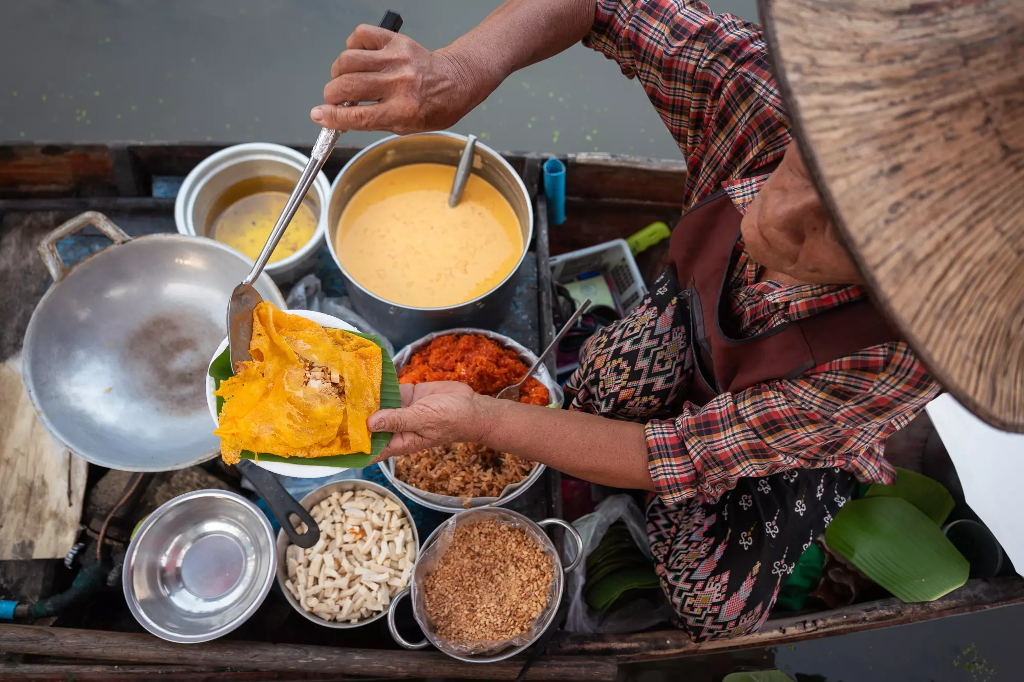 A market trader dishes up an omelette on a boat stall in a floating market