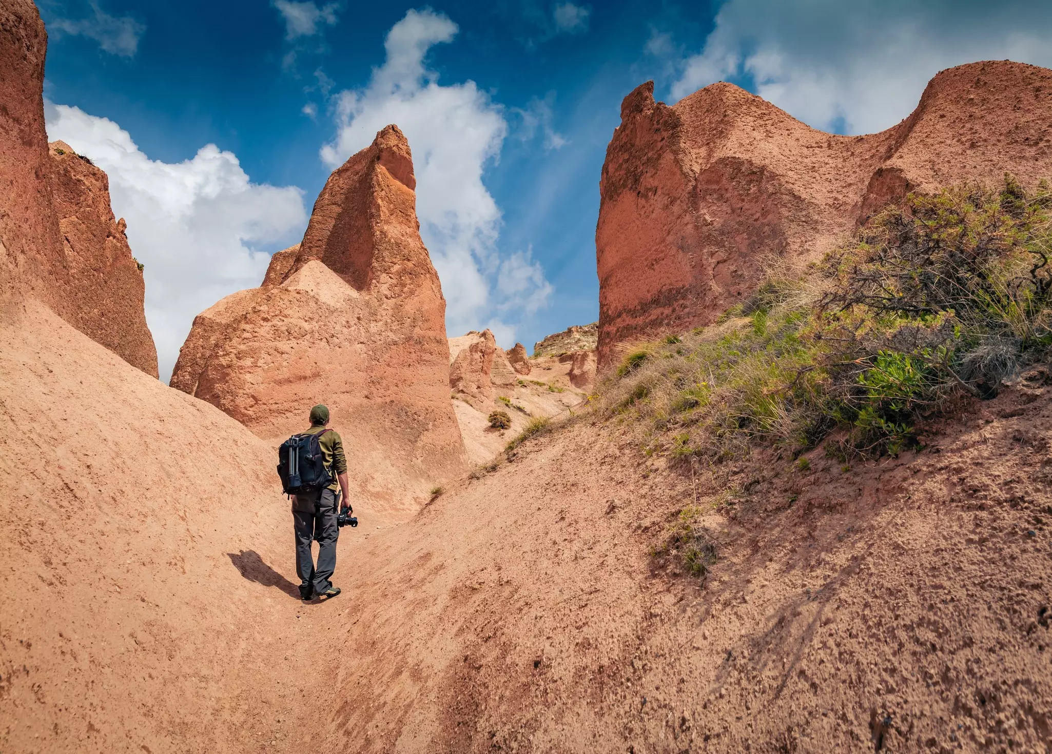 Photographer walks among huge sandstone peaks in Cappadocia. Majestic morning view of of Red Rose valley, Cavusin village location, Turkey, Asia. Traveling concept background., License Type: media, Download Time: 2026-06-25T00:21:50.000Z, User: LP_LHorst, Editorial: false, purchase_order: 56530 - Guidebooks, job: LP Photo Editorial, client: Turkey-18, other: Lyn Horst