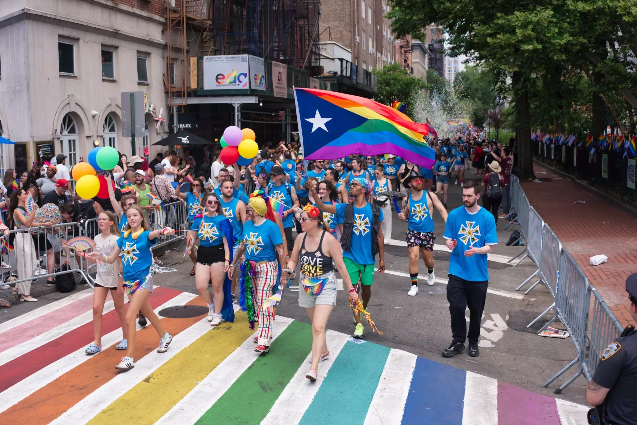 Marchers wearing colorful outfits and stepping across a rainbow crosswalk at the NYC Pride March