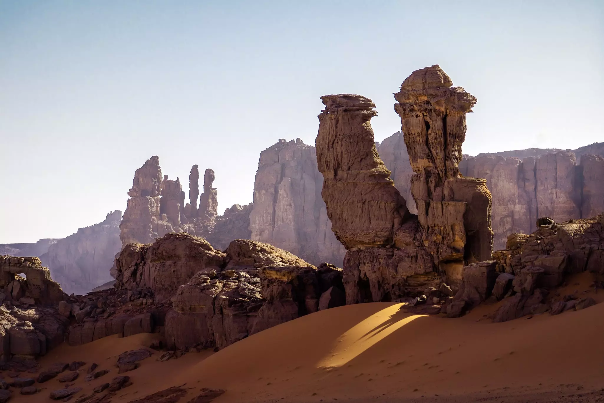 Rock formations top a sand dune in Algeria.