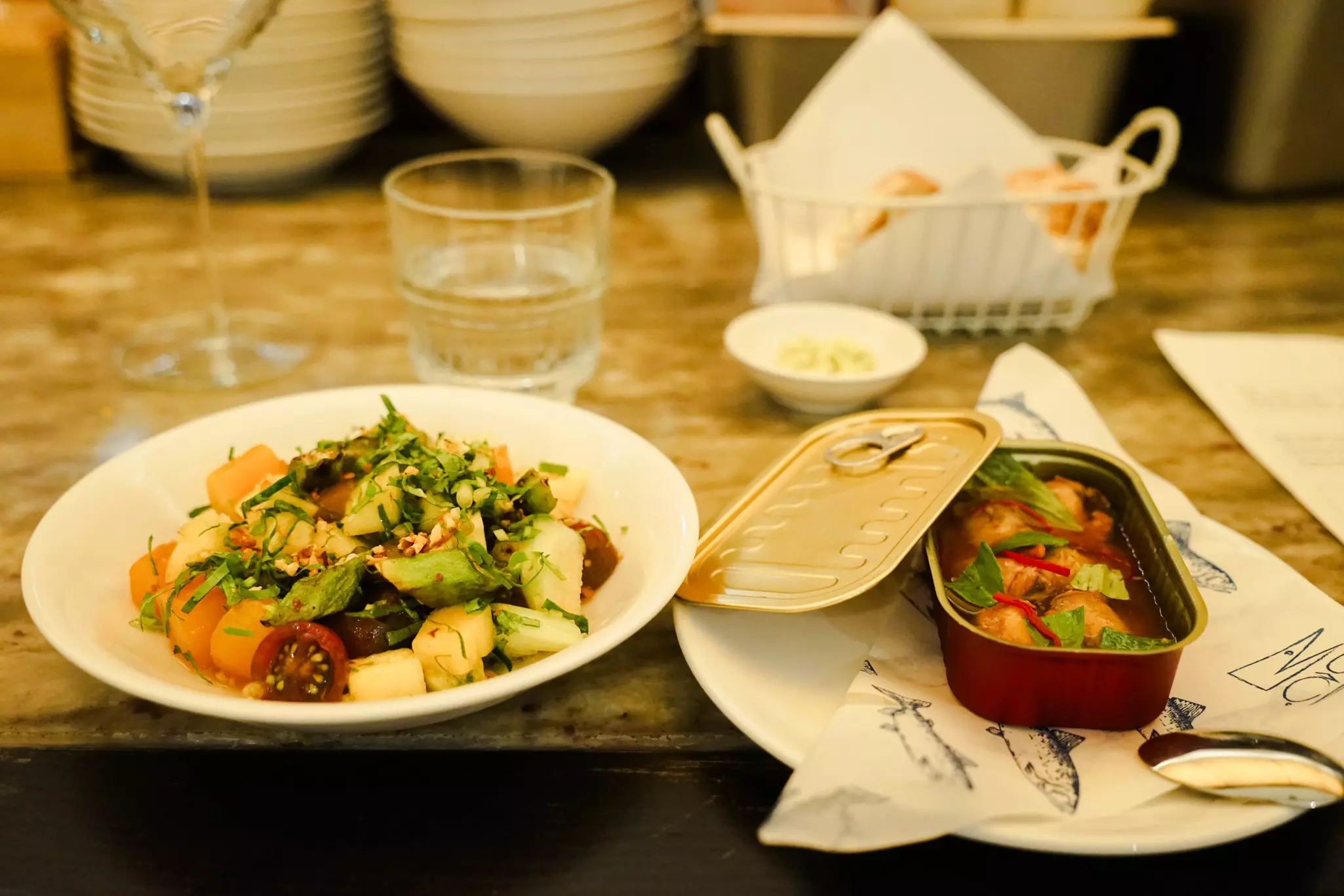 Two seafood dishes are plated and presented on a restaurant table.
