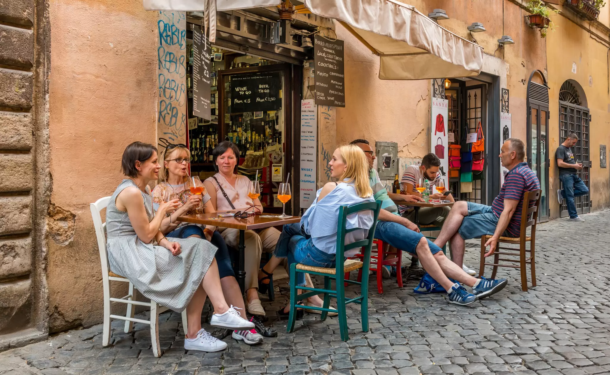 People sipping Aperol spritzes at a cafe in Trastevere, Rome, Italy.