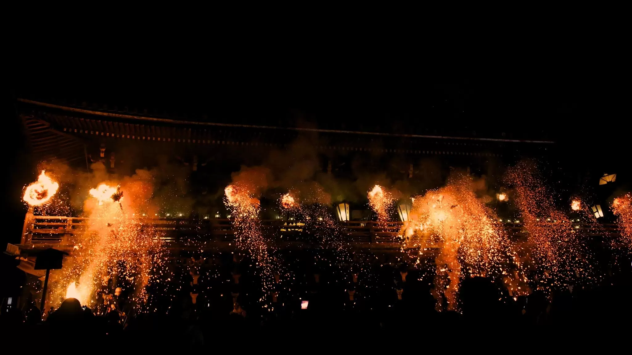 Sparks raining down from a platform at night during a fire festival