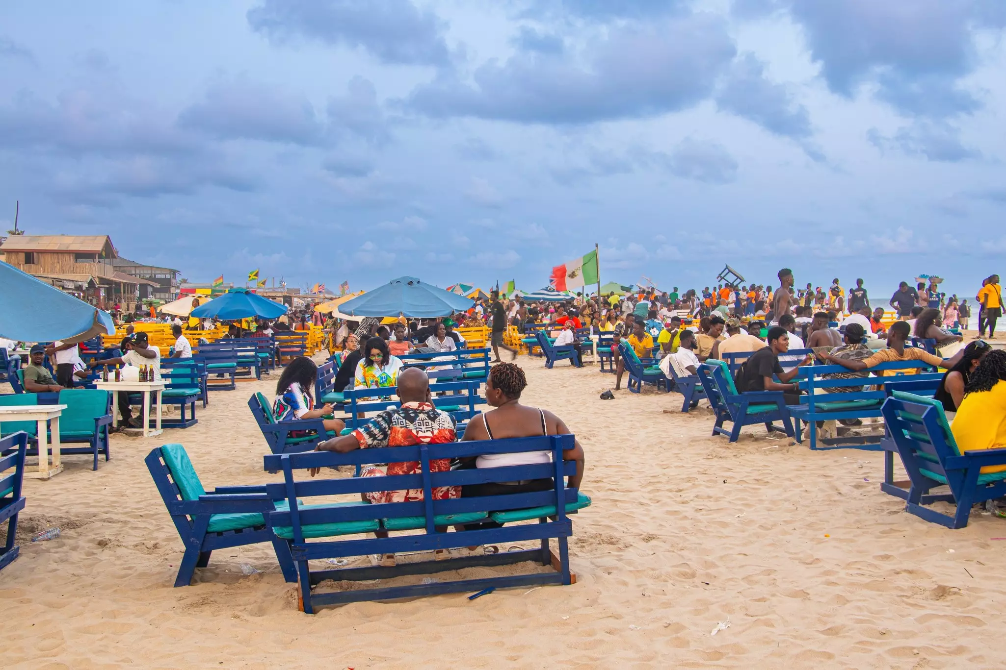 A busy beach with tables crammed with people.