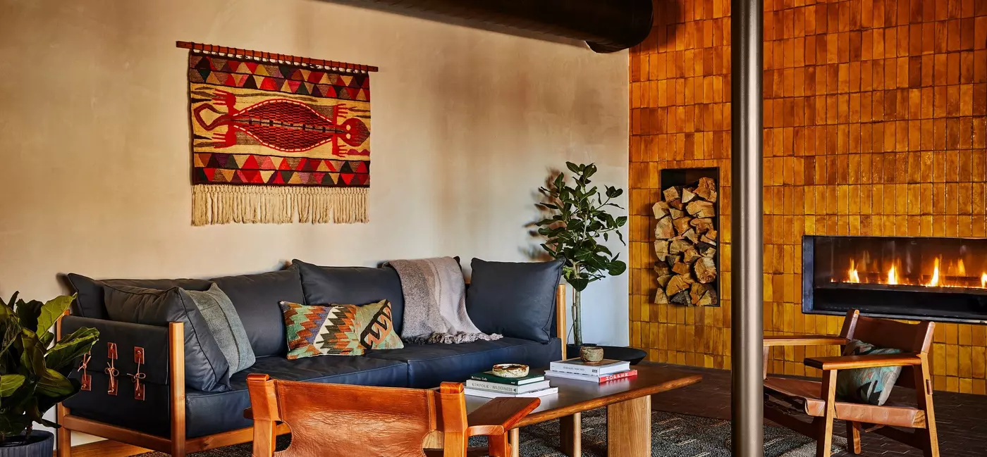 The cozy lobby, with a fireplace, plants, a sofa and chairs, and a coffee table.
