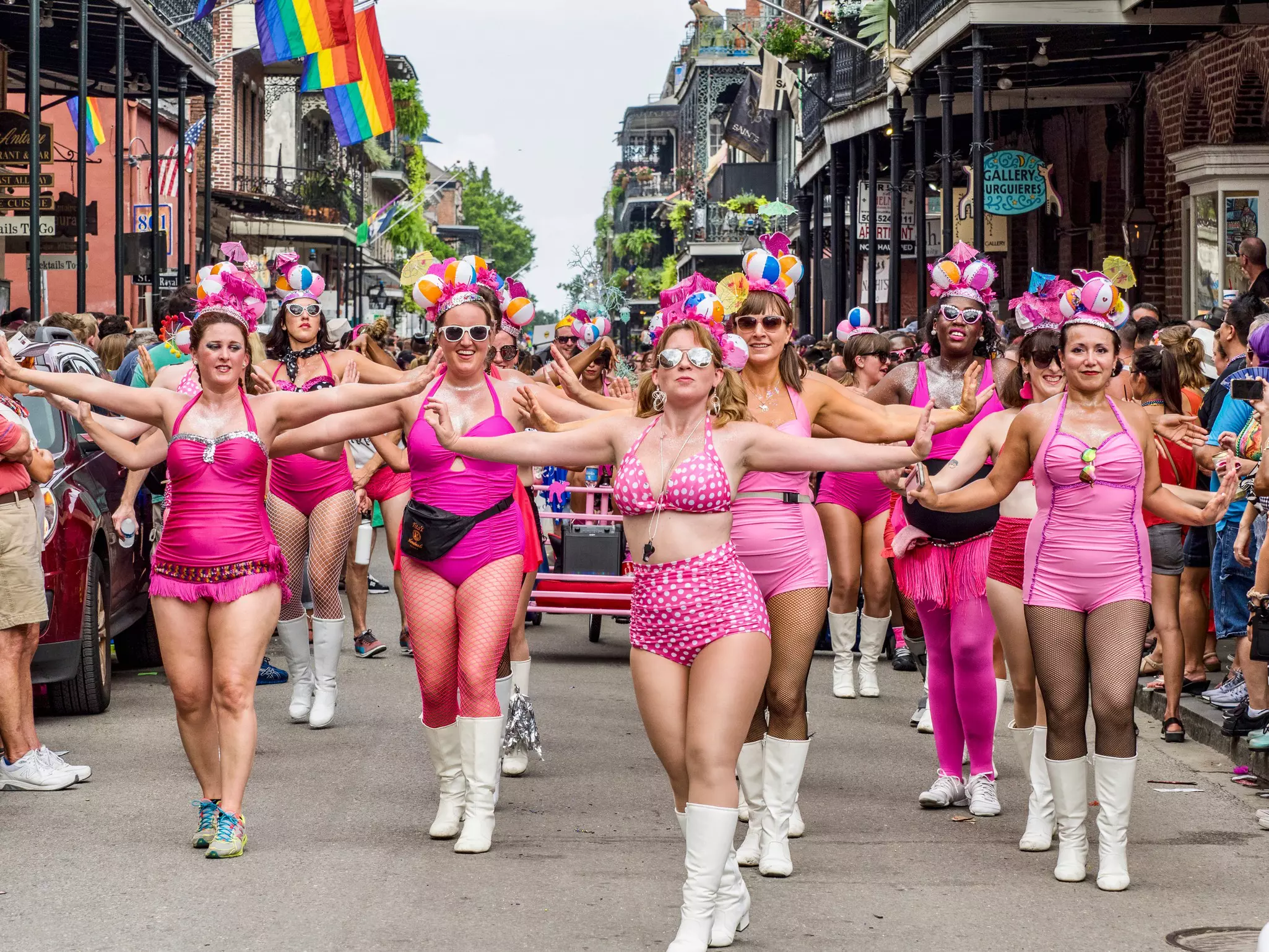 Female revelers wearing hot-pink costumes parade through a street