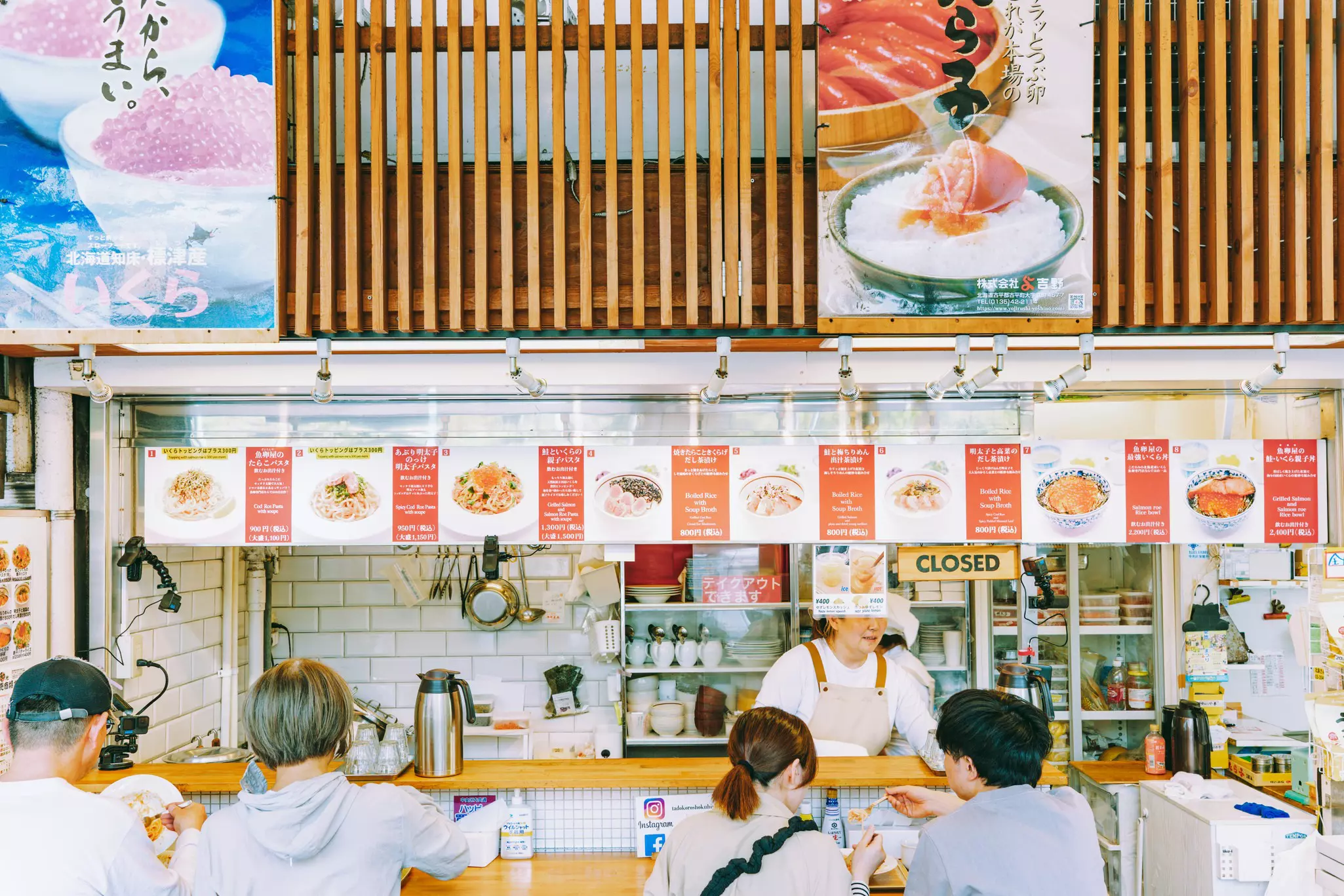 People sit at the counter of a seafood market in Tokyo.