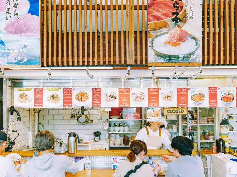 People sit at the counter of a seafood market in Tokyo.