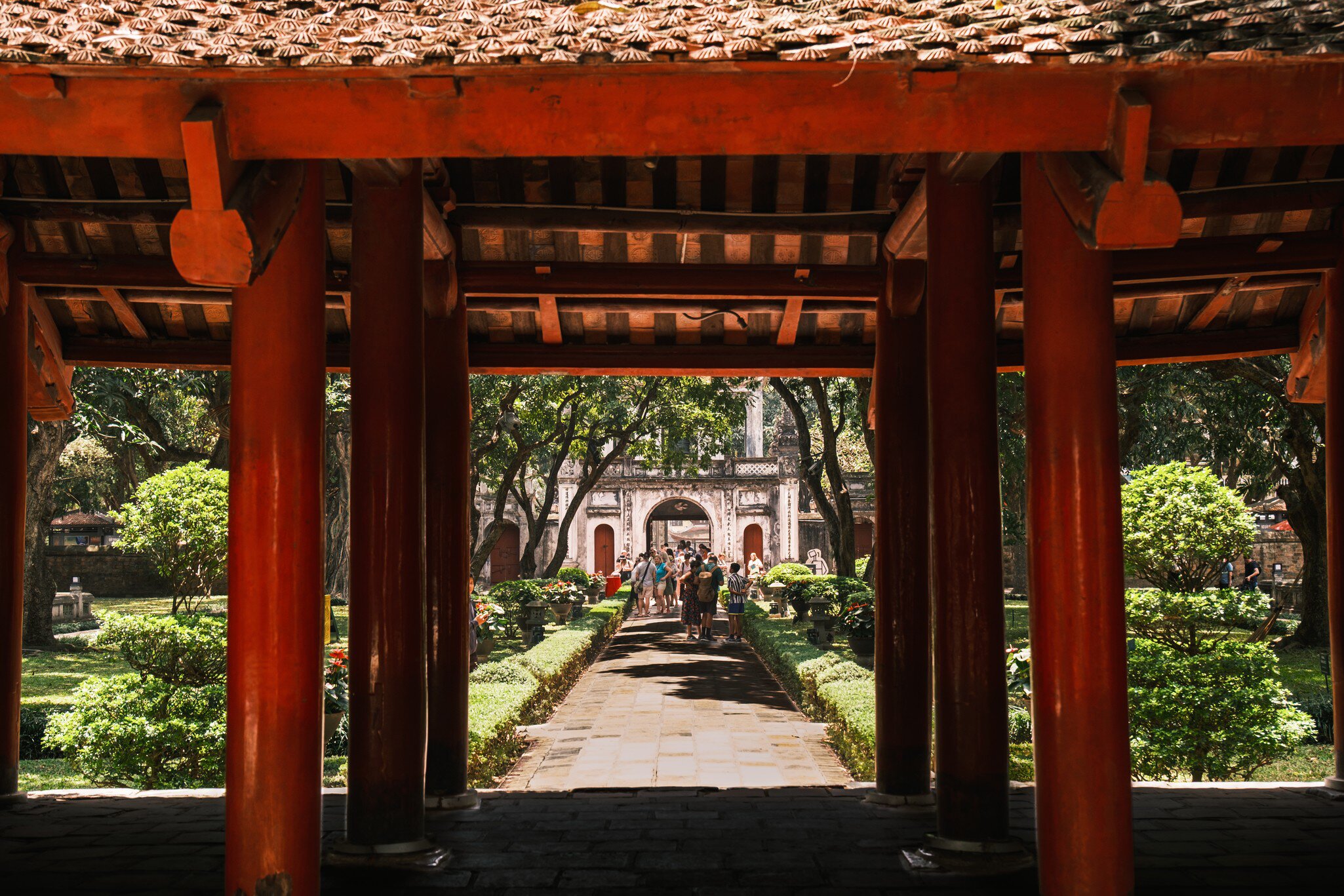 A group of tourists stroll through the lush green gardens in the Temple of Literature, Hanoi.