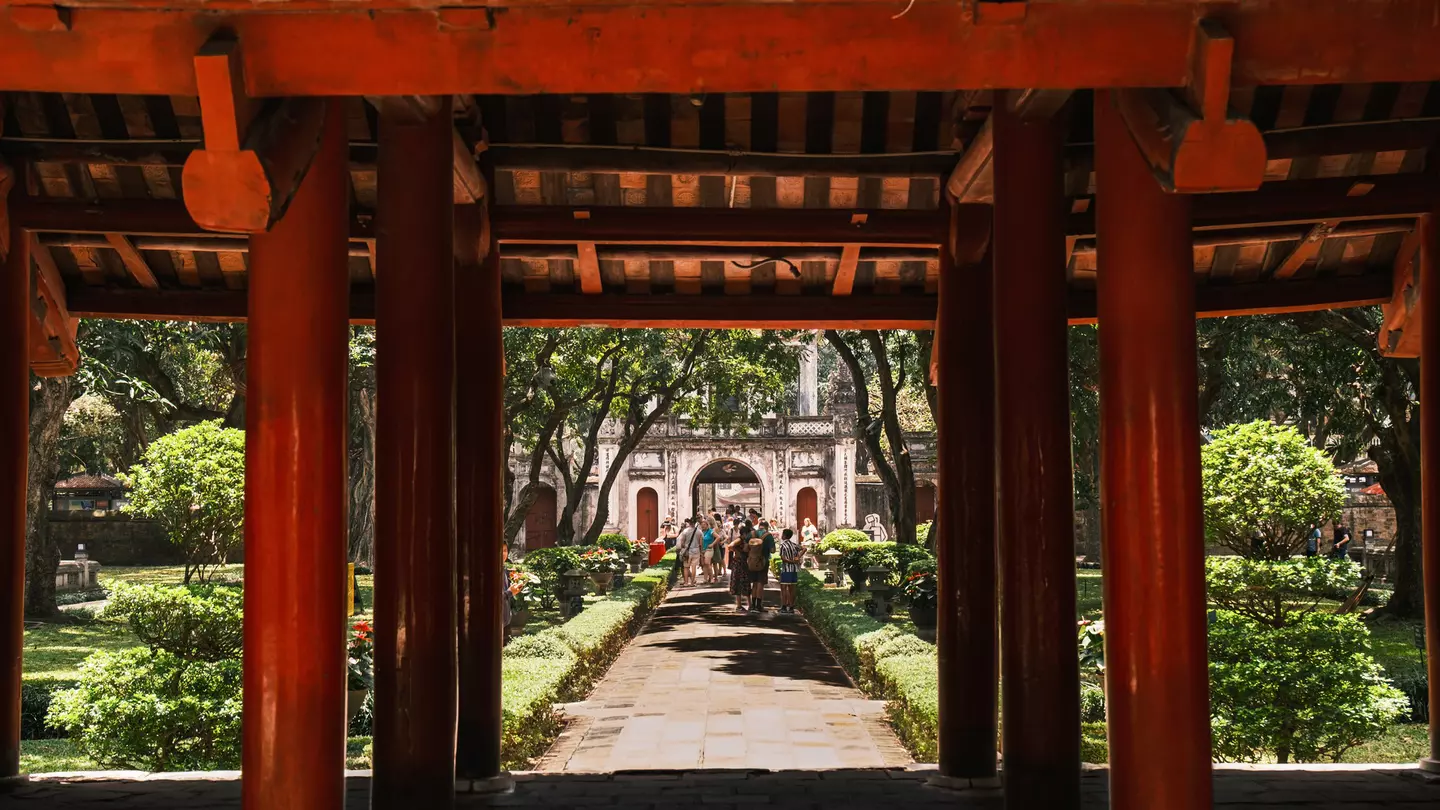A group of tourists stroll through the lush green gardens in the Temple of Literature, Hanoi.