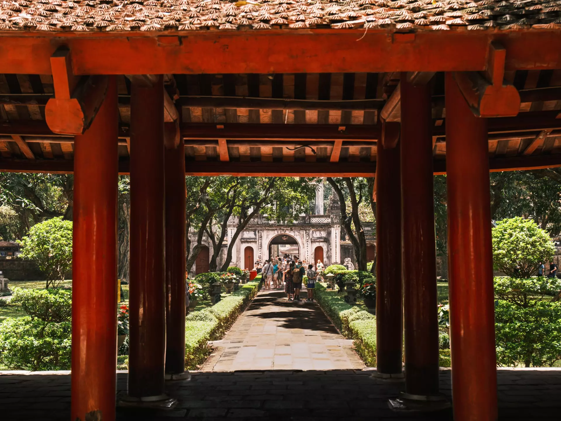 A group of tourists stroll through the lush green gardens in the Temple of Literature, Hanoi.