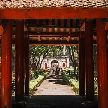 A group of tourists stroll through the lush green gardens in the Temple of Literature, Hanoi.
