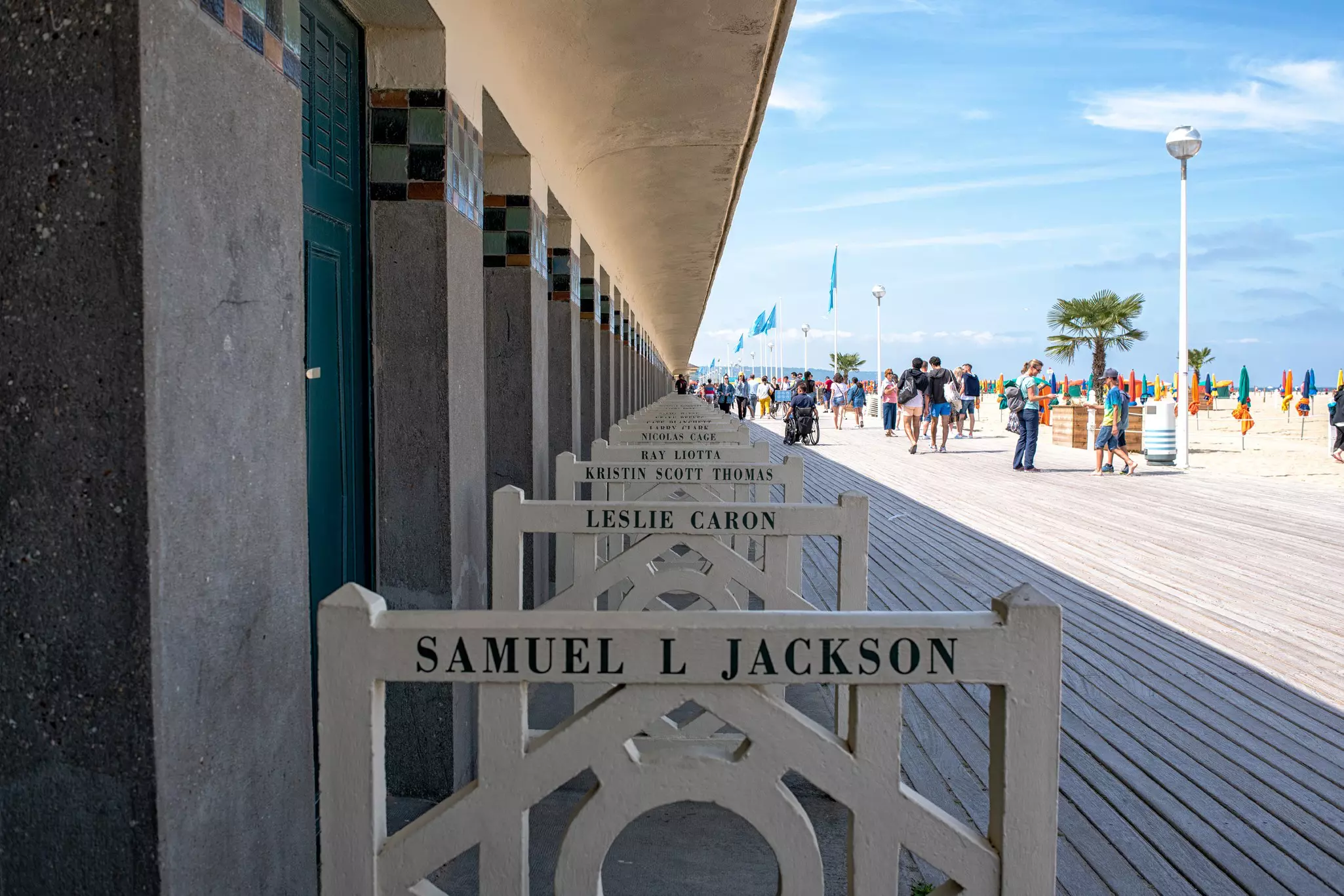 Names are written on railings by cabanas on a seaside promenade.