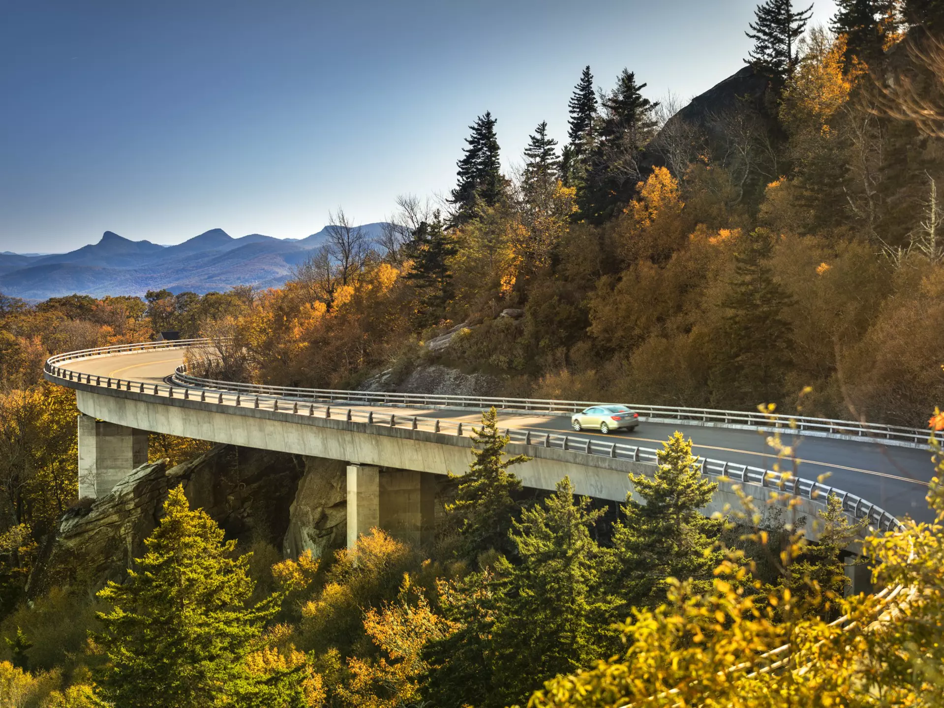 Cars travel on the Linn Cove Viaduct along the Blue Ridge Parkway in fall, North Carolina