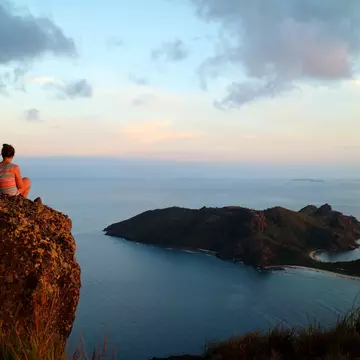 Woman overlooking stunning view over the sea from a rock on a high point in Yasawa, Fiji. Sara Petersson / Shutterstock
