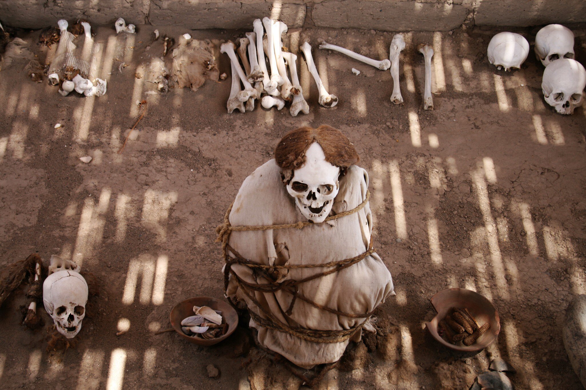 Mummified human remains surrounded by bones at Chauchilla Cemetery, Peru.