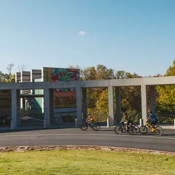 People cycling by a large museum.