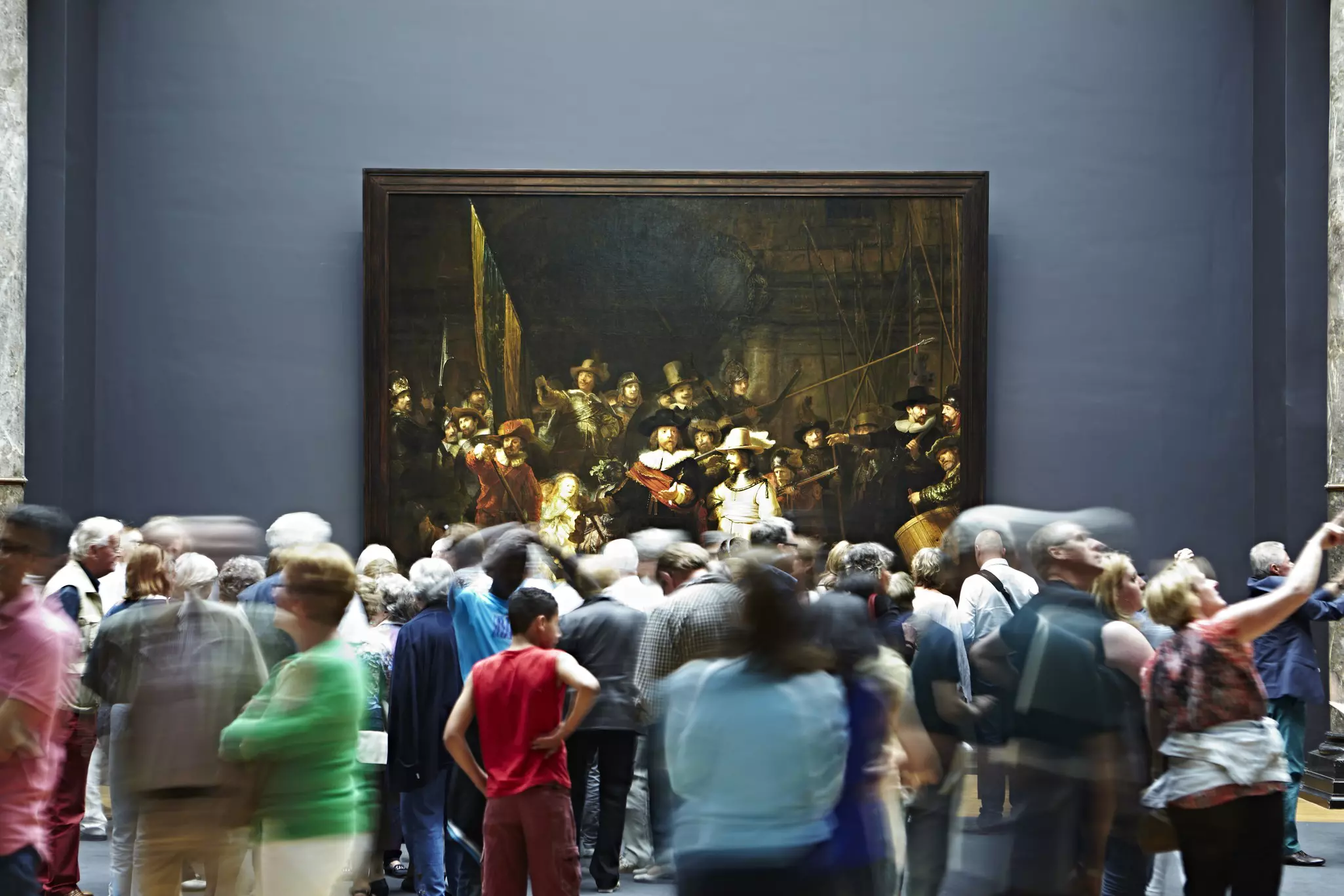 Art lovers looking at a large painting in a museum