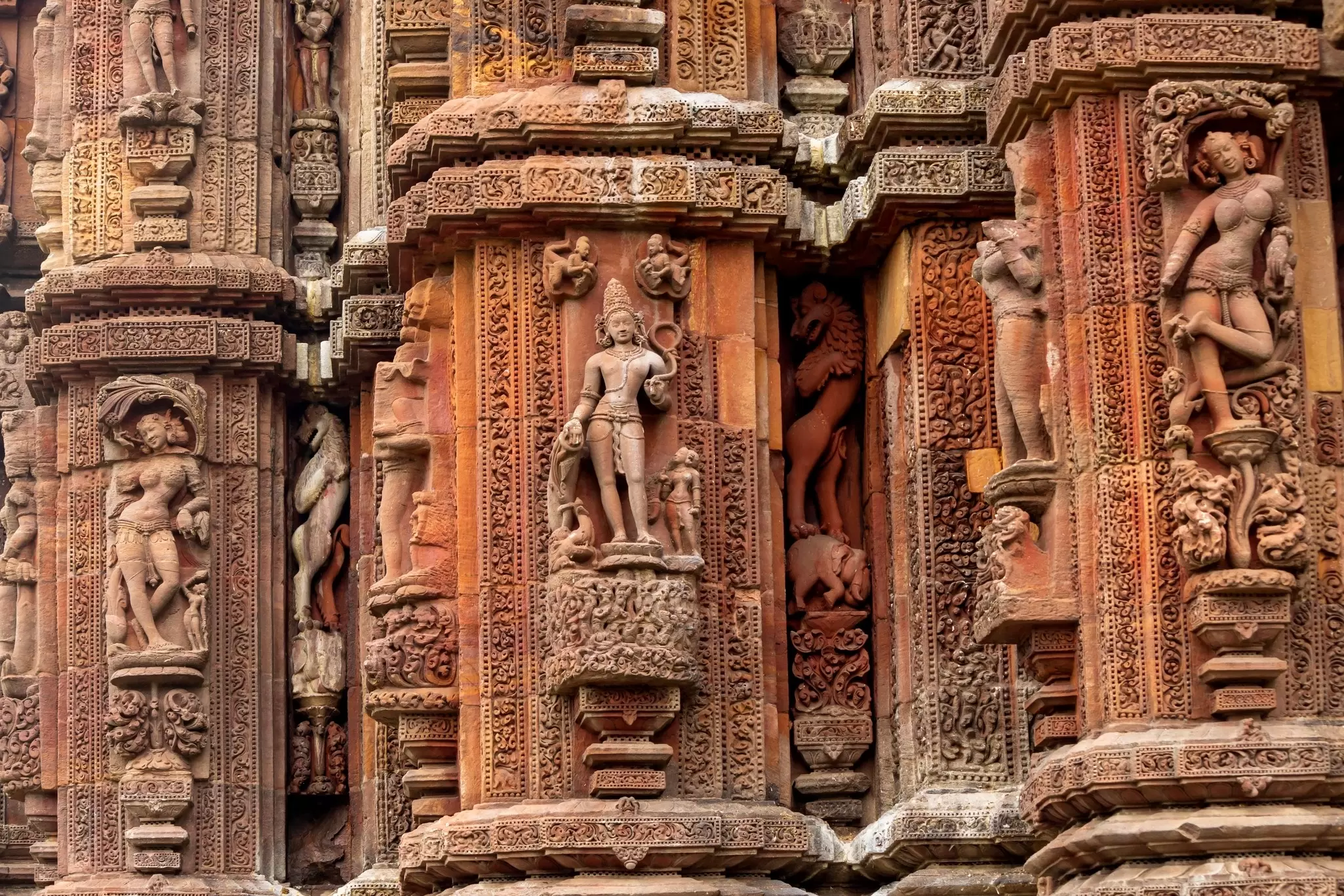 Intricate carvings on a red sandstone temple facade.