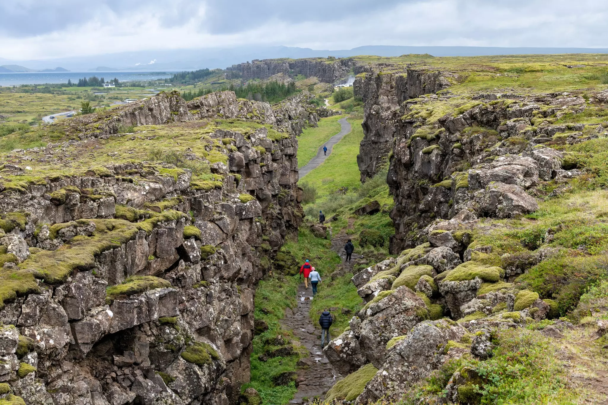 People walk in a valley between two rock formations.