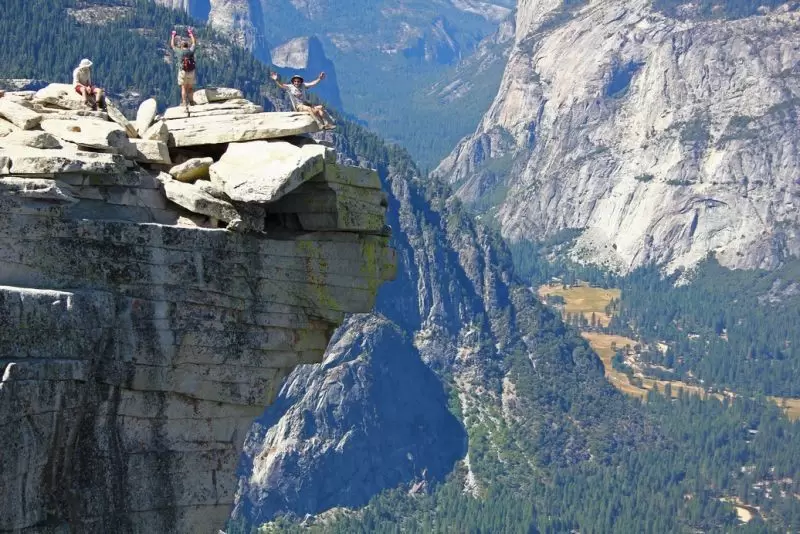 Hikers celebrate on the Monolith at the summit of Half Dome in Yosemite National Park, California.