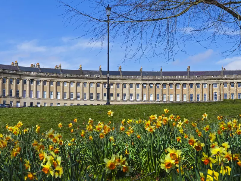 A springtime view of the beautiful Royal Crescent in Bath, Somerset, with daffodils in the foreground