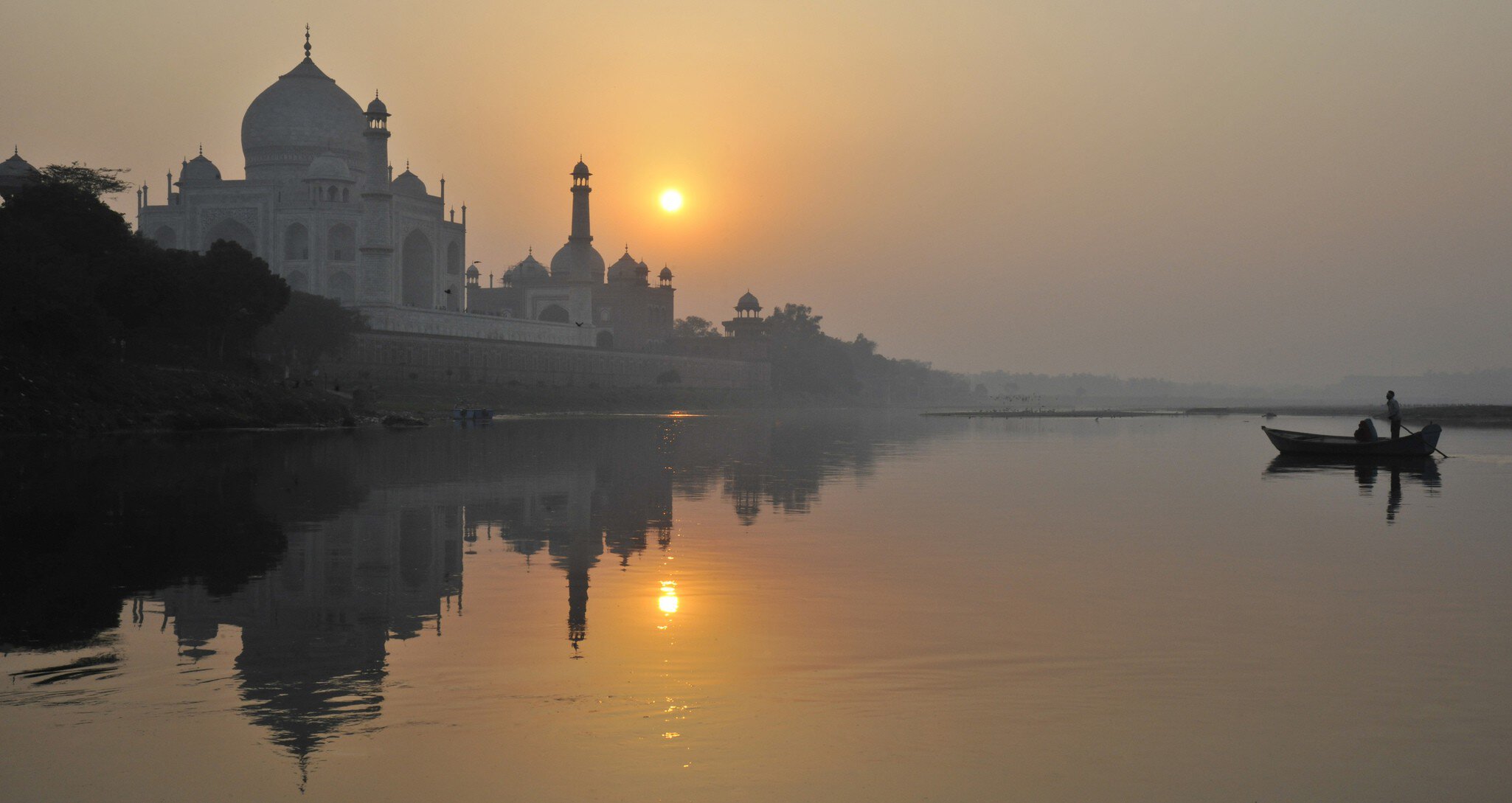 Boat padding on Yamuna River beside Taj Mahal.