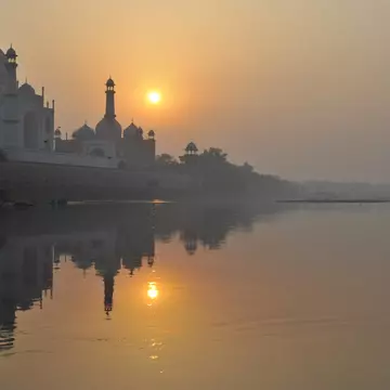 Boat padding on Yamuna River beside Taj Mahal.