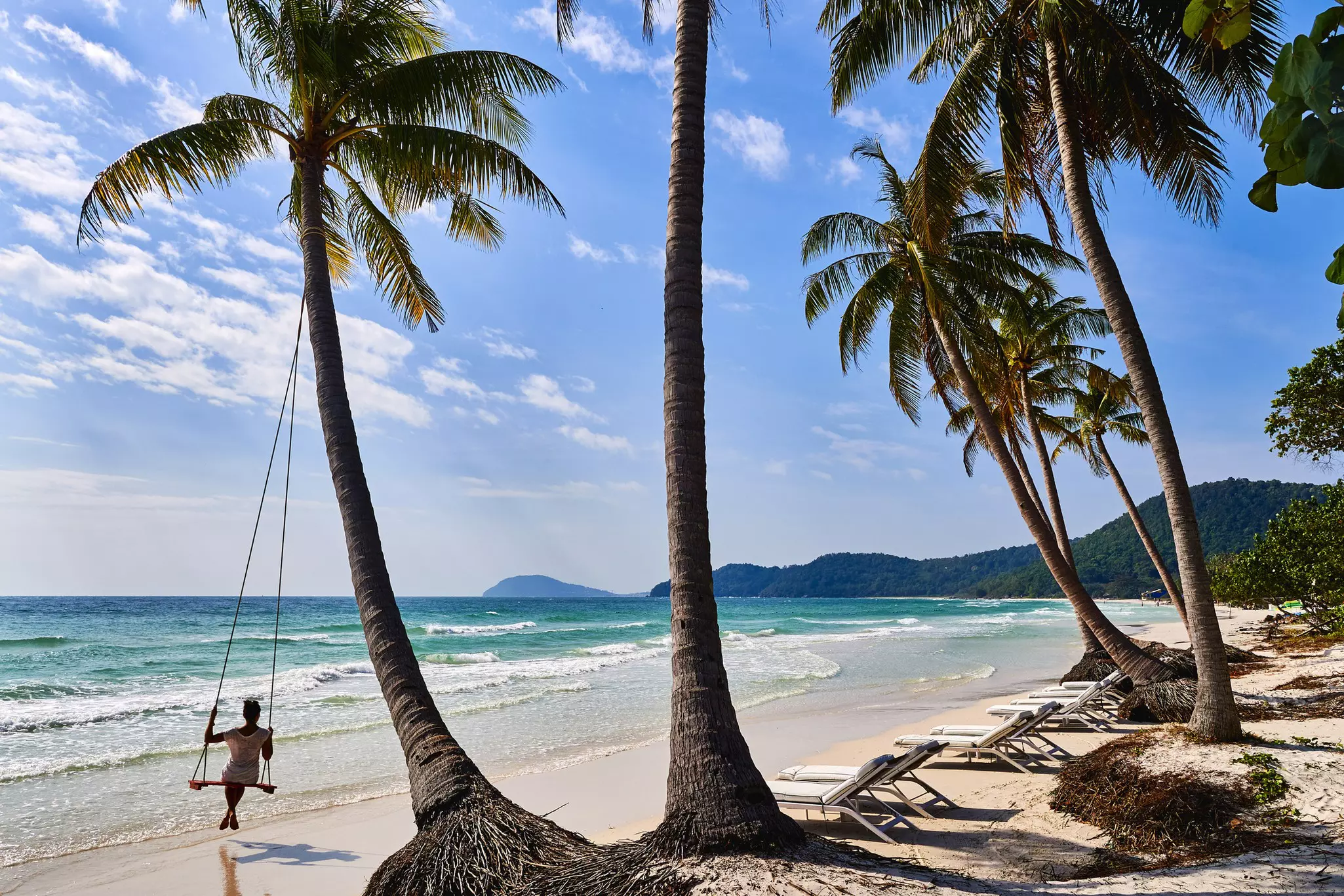 A woman sits on a tree swing on Bai Bien Sao beach on Phu Quoc island, Vietnam.
