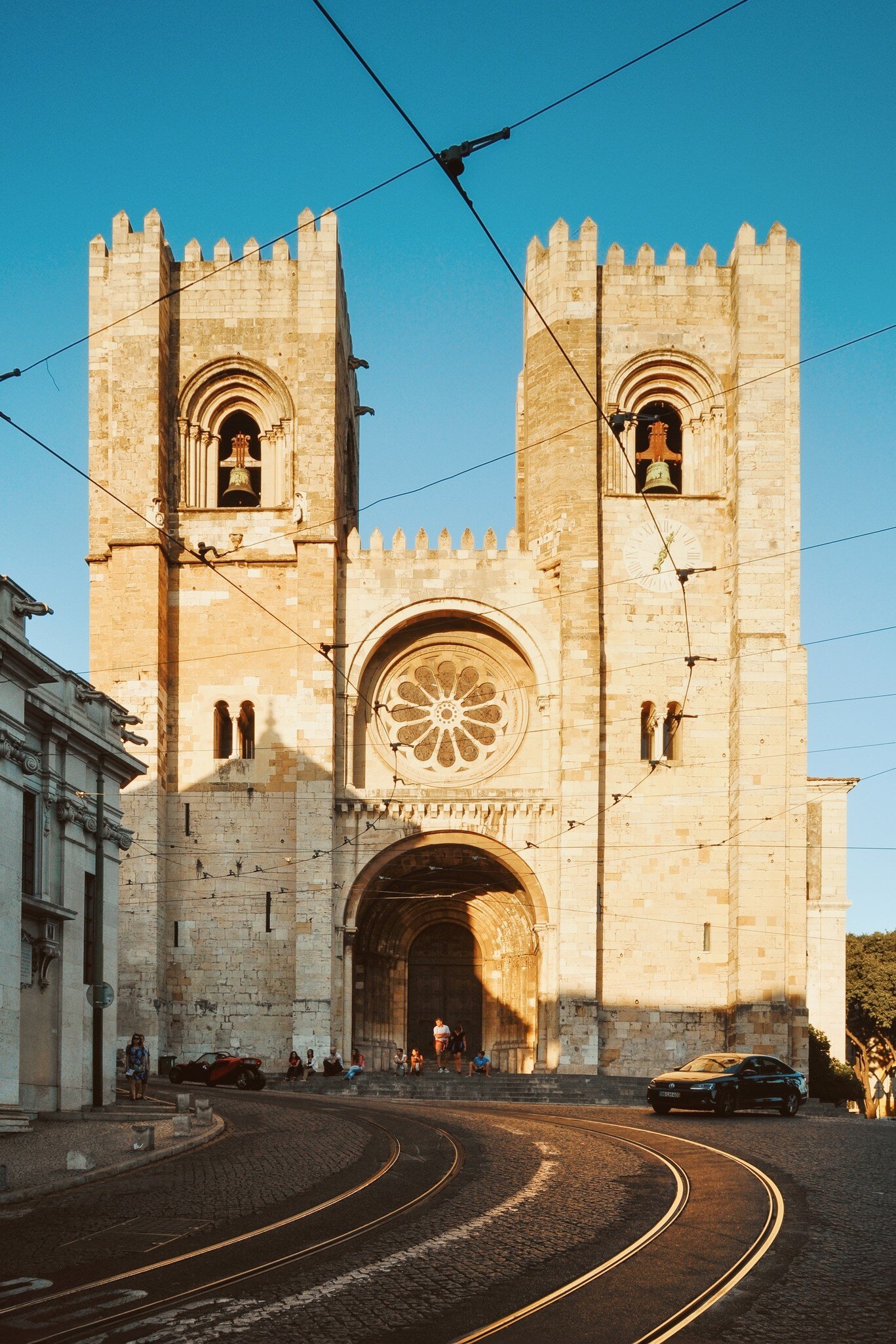 Lisbon Cathedral at sunset on a half-empty street with curvy tram tracks, in Lisbon, Portugal.