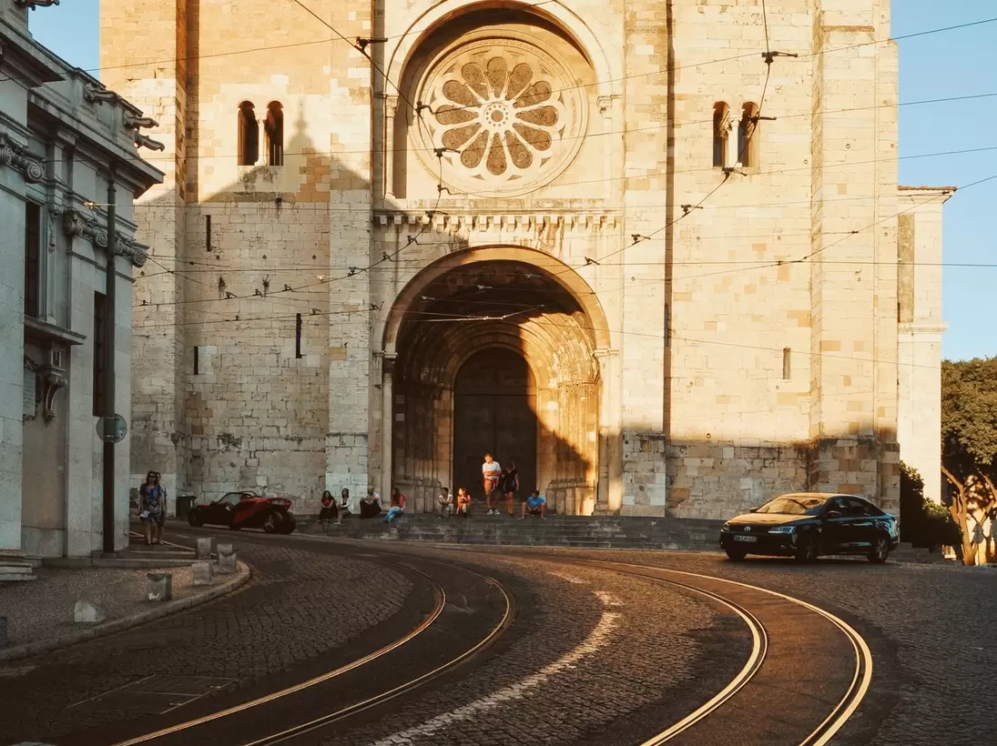 Lisbon Cathedral at sunset on a half-empty street with curvy tram tracks, in Lisbon, Portugal.