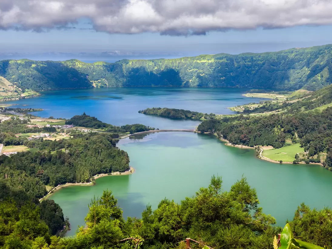 A series of clouds overlooks twin blue and green lakes of Lake Sete Cidades from Vista do Rei viewpoint in Sao Miguel, Azores.