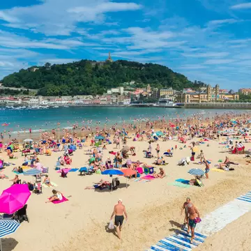 People swimming and tanning on Playa de la Concha in San Sebastián, Spain.